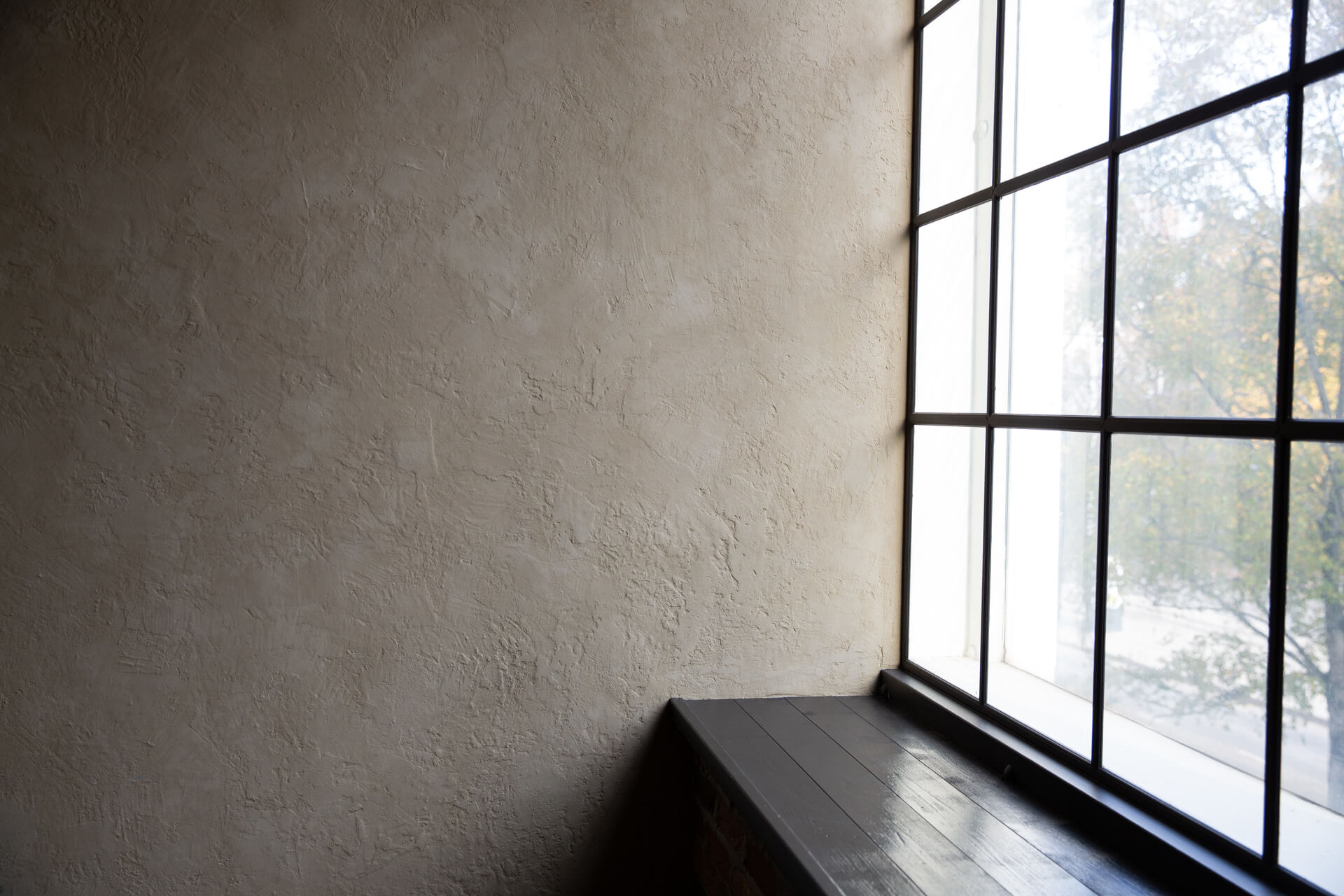 A light relief wall with a tall window and a wide windowsill